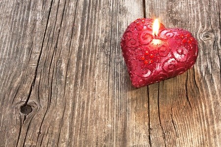 12537949 - red heart shaped candle on wooden background