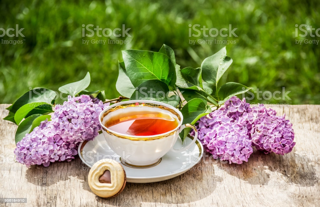 Cup of tea and lilac flowers. Breakfast in the garden. Morning tea