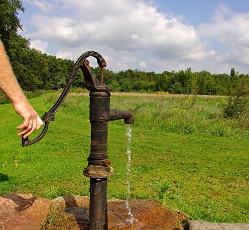 Old well pump with water stream.