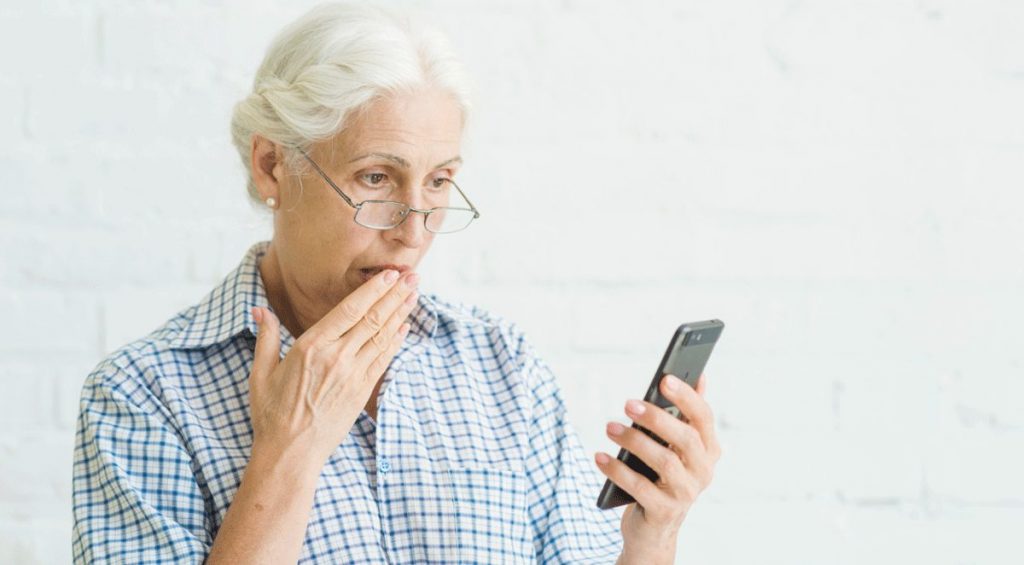 Frau blickt entsetzt auf das Smartphone
