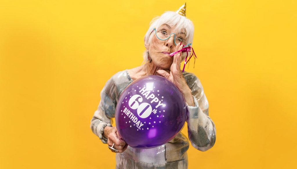 Frau mit Ballon mit Glüclwunsch-Spruch zum 60. Geburtstag.