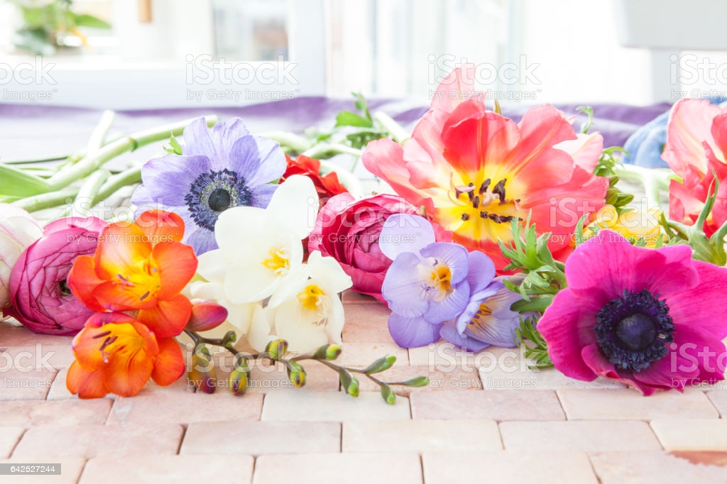Bunte Fruehlingsblumen auf rustikalem Hintergrund aus Steinfliesen
