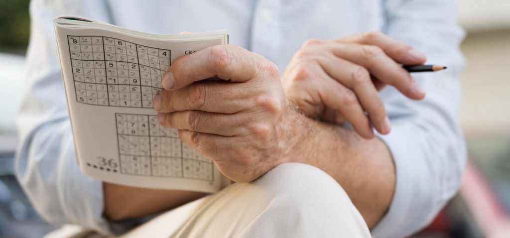 Älterer Mann mit Sudoku Heft