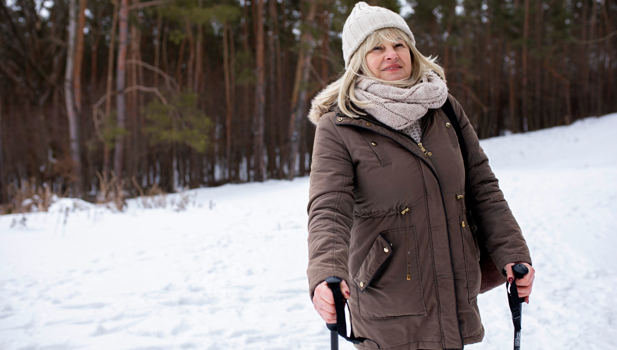 Seniorin wandert durch den Schnee