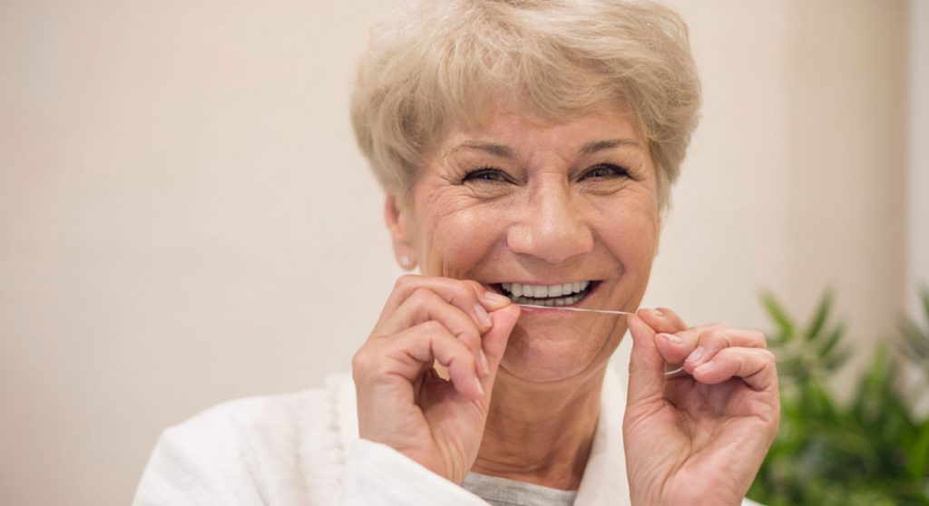 Seniorin mit Zahnseide
